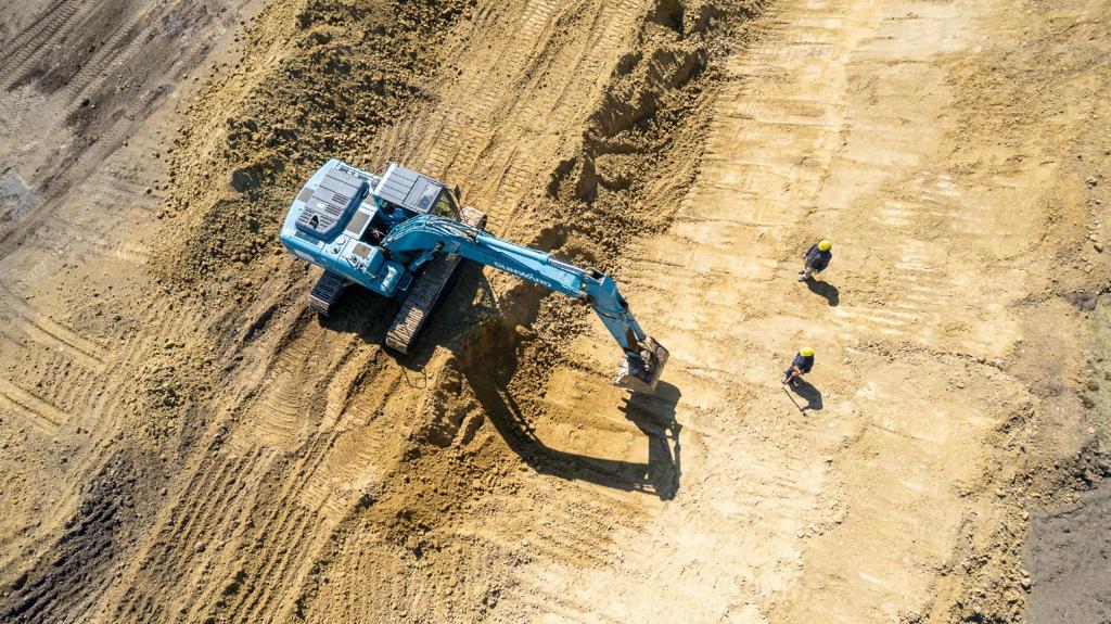 Vista cenital de la excavadora perfilando con dos operarios