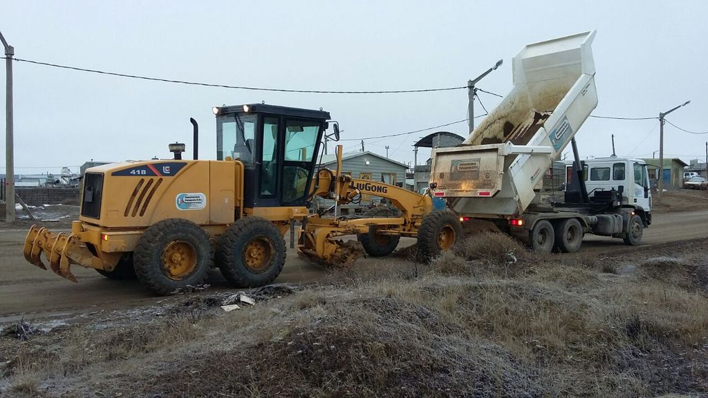 Motoniveladora y camión volcador en un camino