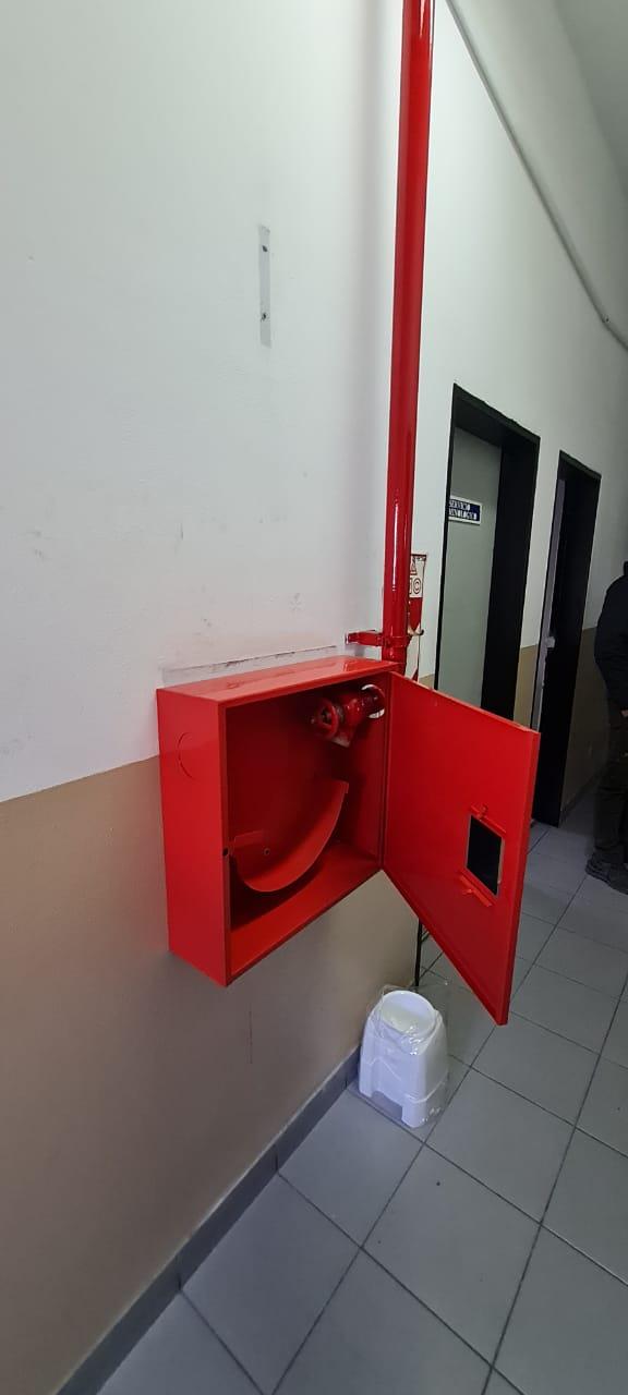 Gabinete hidrante rojo instalado en un pasillo