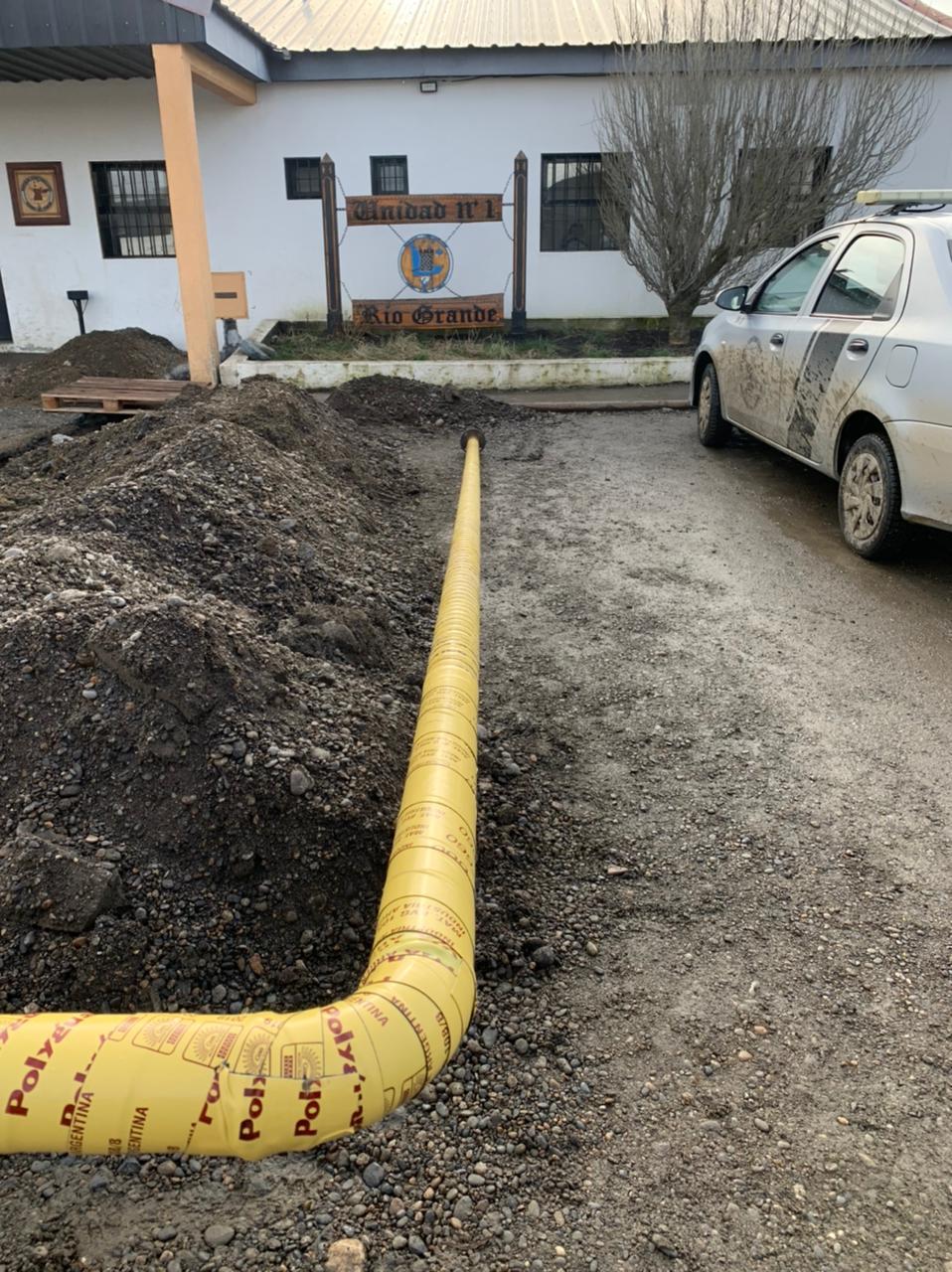 Cañería revestida en amarillo tendida en la zanja junto al edificio