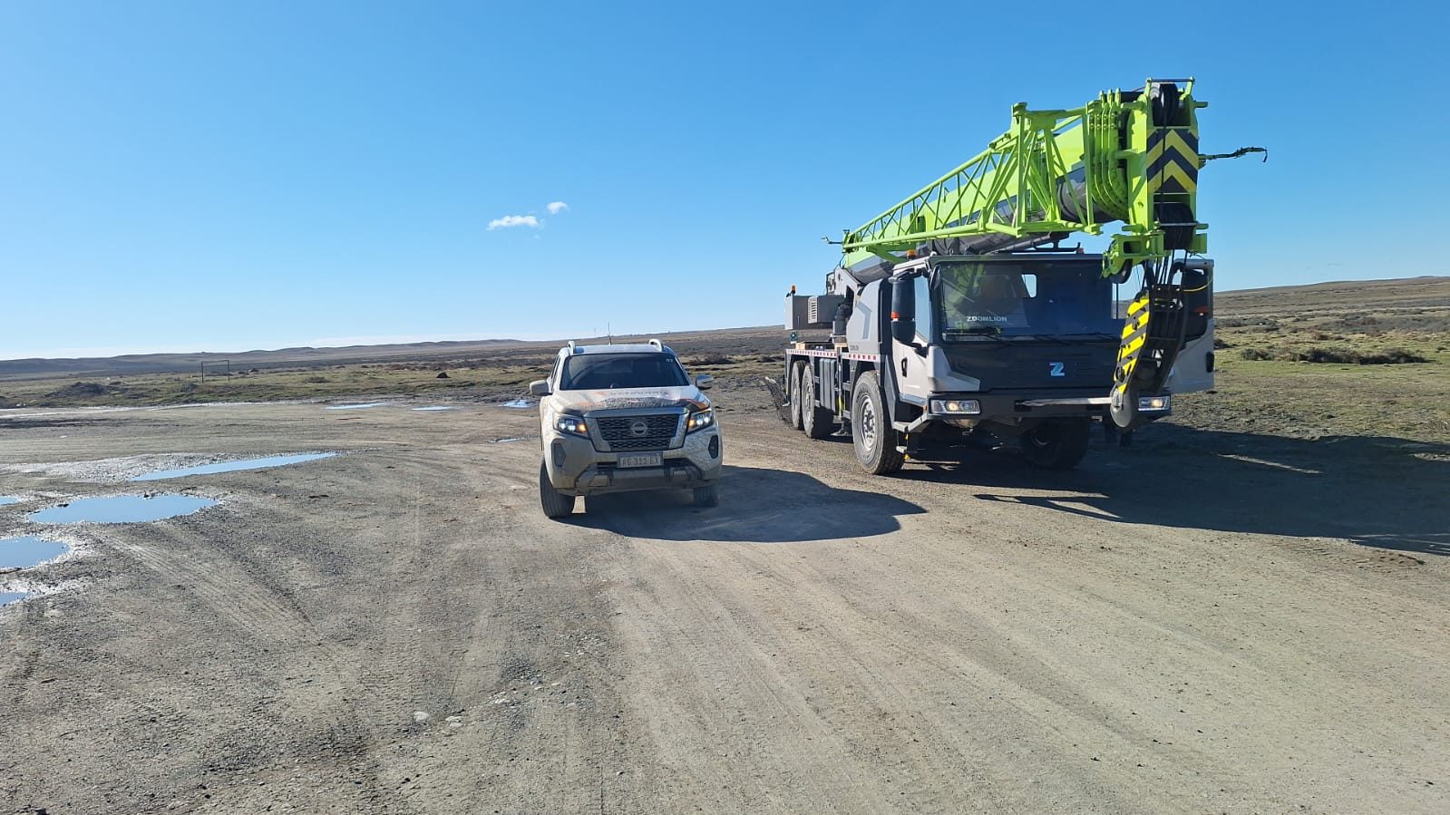 Grúa y camioneta en un camino de ripio