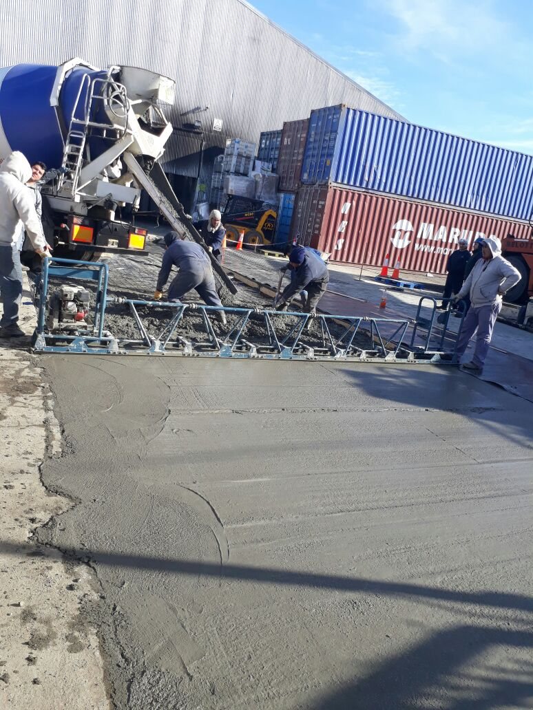 Cuadrilla hormigonando con regla vibratoria junto a los contenedores