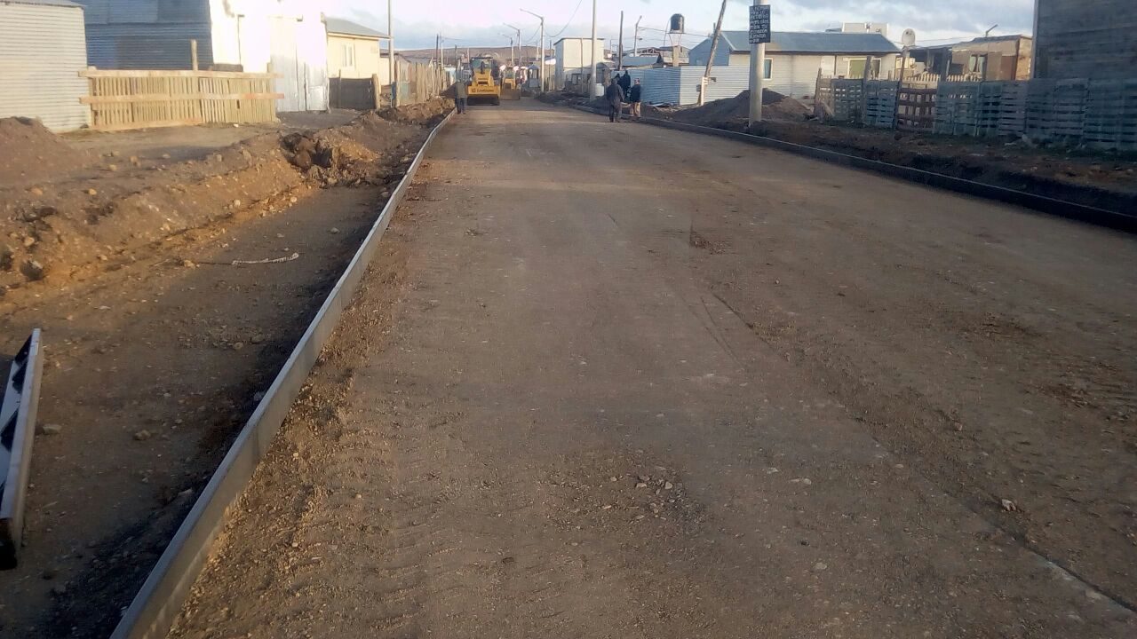 Calle con cordones colocados y equipos trabajando
