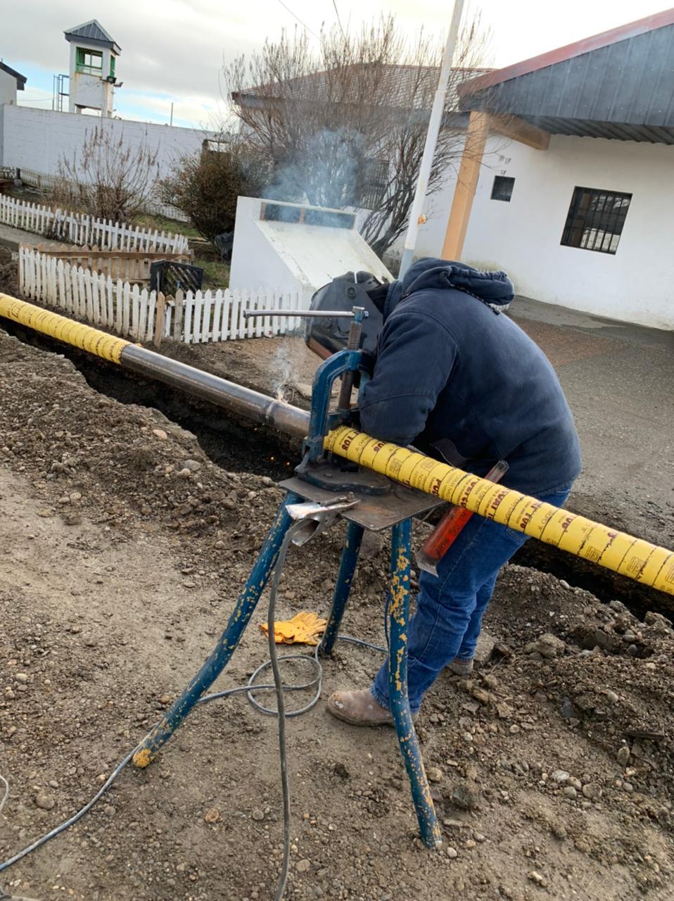 Soldador uniendo tramos de la cañería troncal junto a la zanja