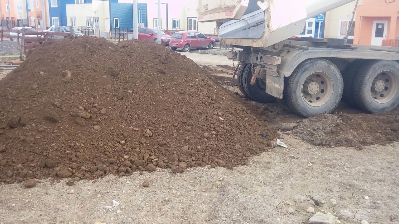 Camión volcador descargando suelo en un barrio