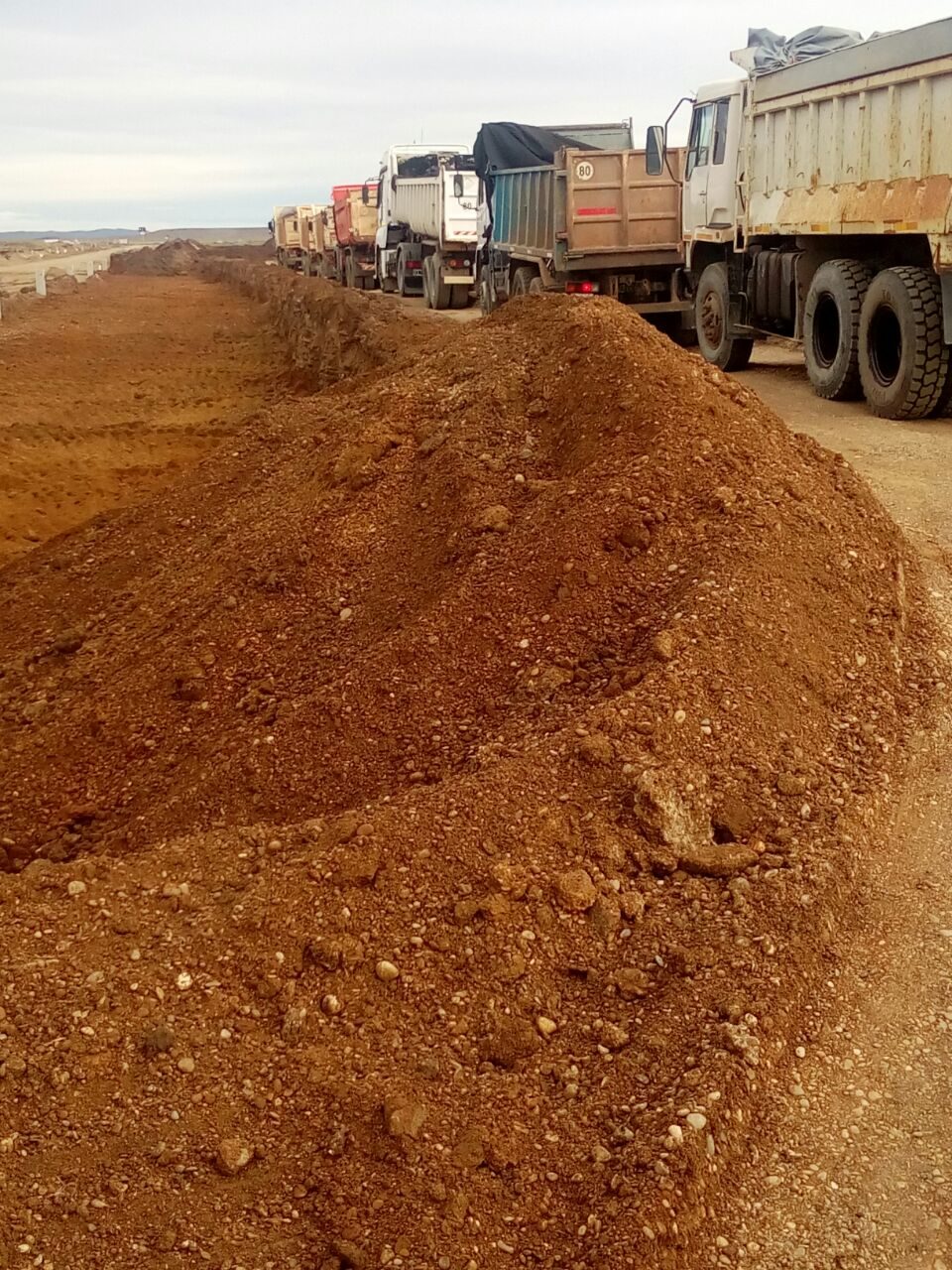 Fila de camiones volcadores junto al suelo acopiado