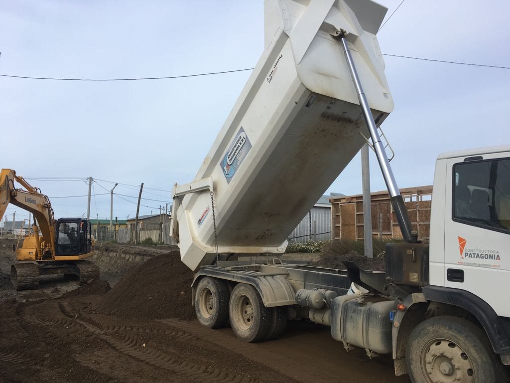 Camión volcador de la empresa descargando suelo junto a la excavadora