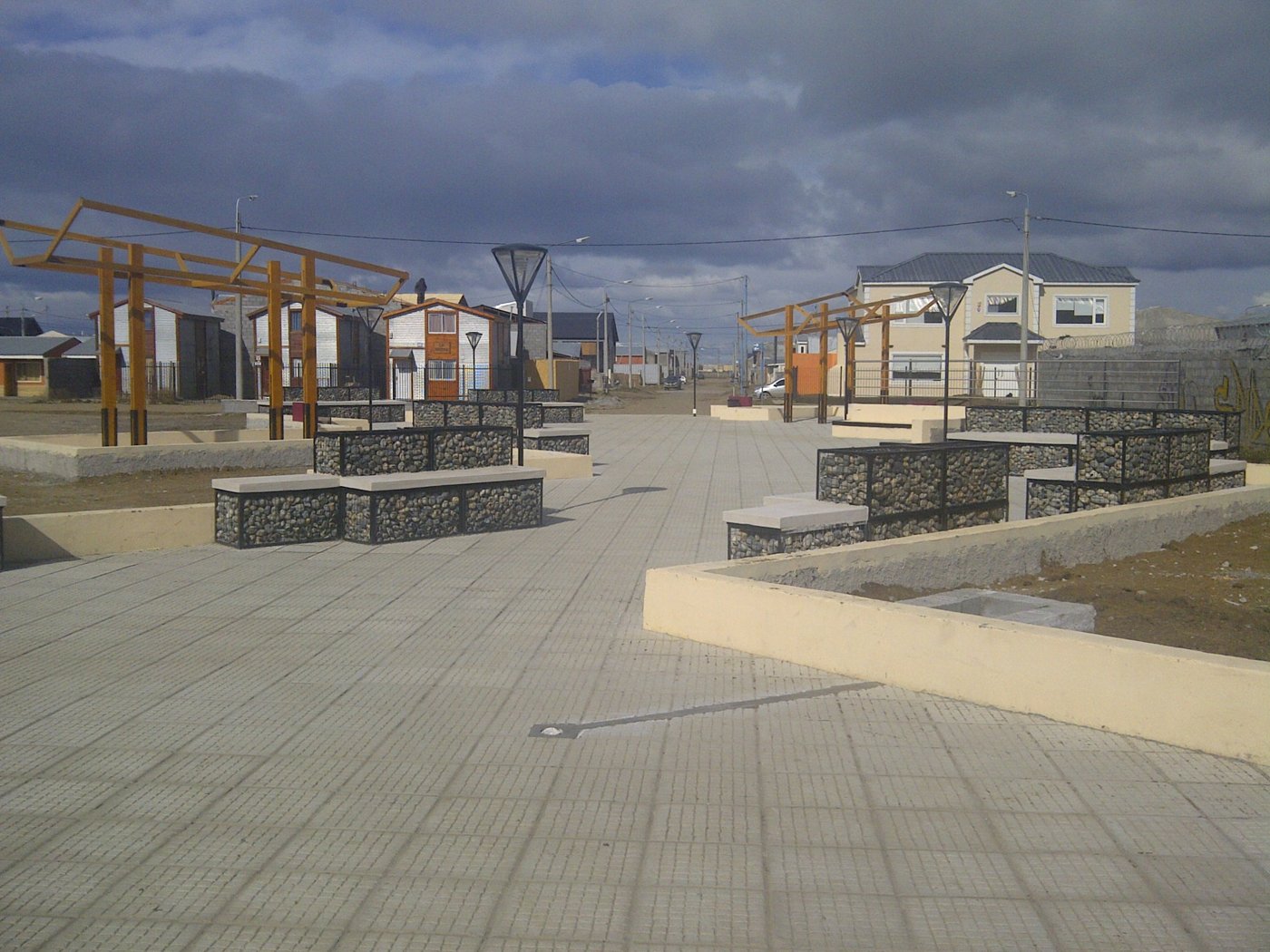 Plaza terminada con gaviones, pérgolas y luminarias