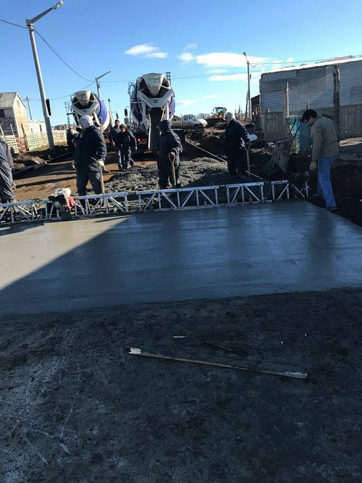 Dos camiones mixer descargando hormigón frente a la regla vibratoria